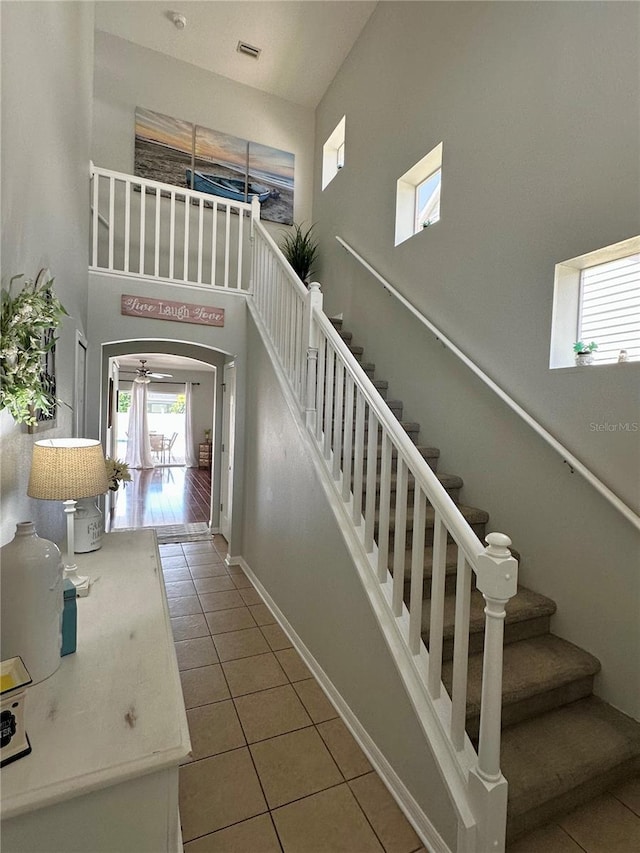 9808 Riverchase Dr, New Port Richey, FL 34655 - staircase featuring tile patterned flooring, a towering ceiling, healthy amount of natural light, arched walkways, and baseboards