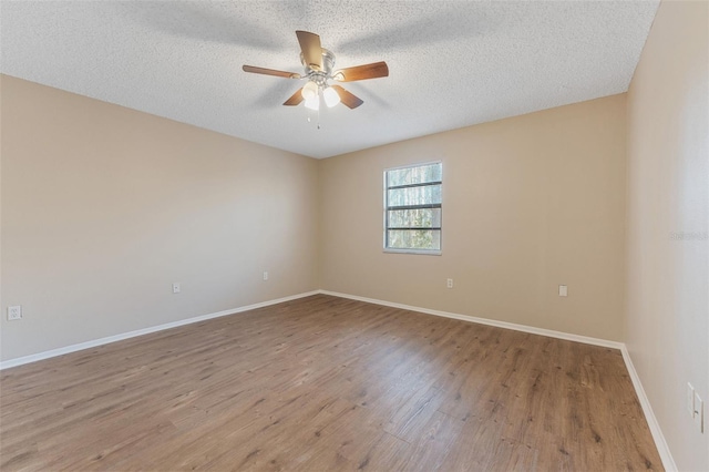 empty room with wood finished floors, ceiling fan, a textured ceiling, and baseboards