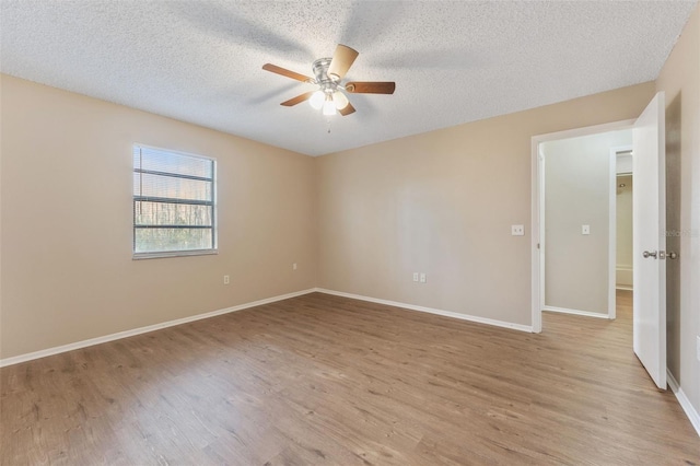 spare room featuring ceiling fan, light wood-type flooring, a textured ceiling, and baseboards