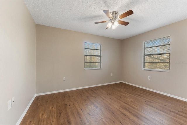 empty room with wood finished floors, ceiling fan, a textured ceiling, and baseboards