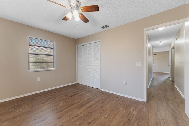 unfurnished bedroom featuring wood finished floors, a closet, baseboards, a textured ceiling, and ceiling fan