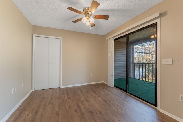 unfurnished bedroom with wood finished floors, access to exterior, a textured ceiling, baseboards, and two closets