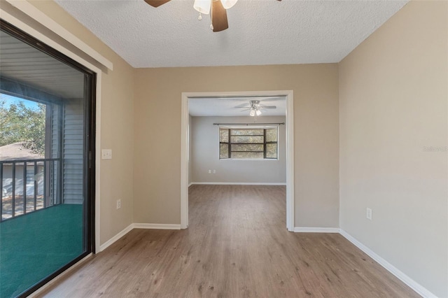 empty room featuring ceiling fan, wood finished floors, baseboards, and a textured ceiling