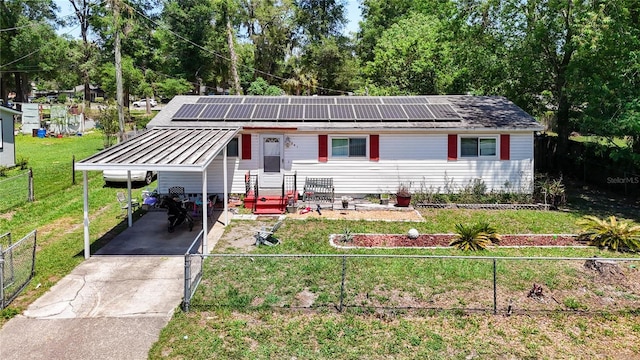 view of front of home with concrete driveway, solar panels, a carport, and view of scattered trees