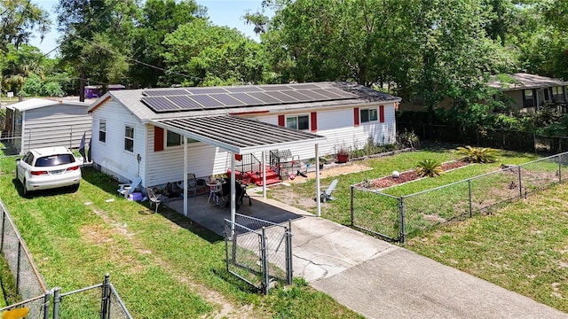 view of front facade with a gate, driveway, and roof mounted solar panels