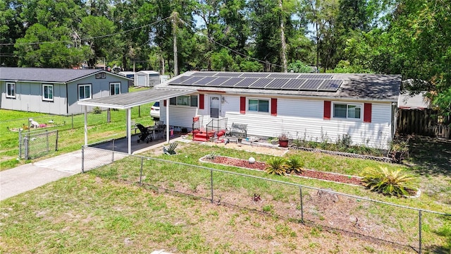 single story home featuring a carport, concrete driveway, entry steps, solar panels, and view of scattered trees