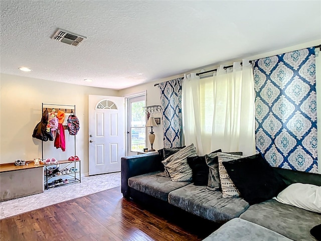 living area featuring wood-type flooring, a textured ceiling, and baseboards