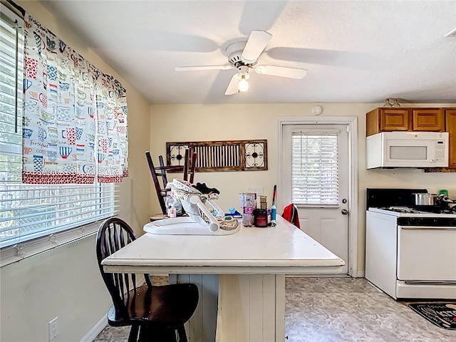 kitchen with white appliances, brown cabinets, ceiling fan, baseboards, and light countertops