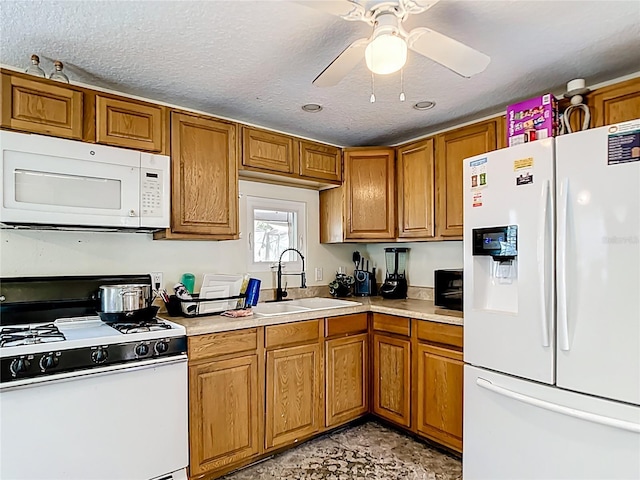 kitchen featuring white appliances, brown cabinets, a sink, light countertops, and a textured ceiling