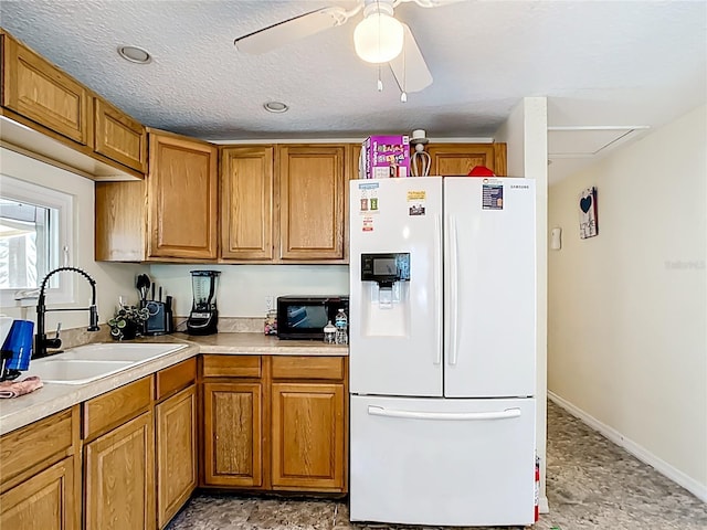 kitchen featuring white refrigerator with ice dispenser, a sink, brown cabinetry, black microwave, and a ceiling fan