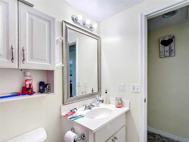 bathroom featuring vanity, toilet, and a textured ceiling