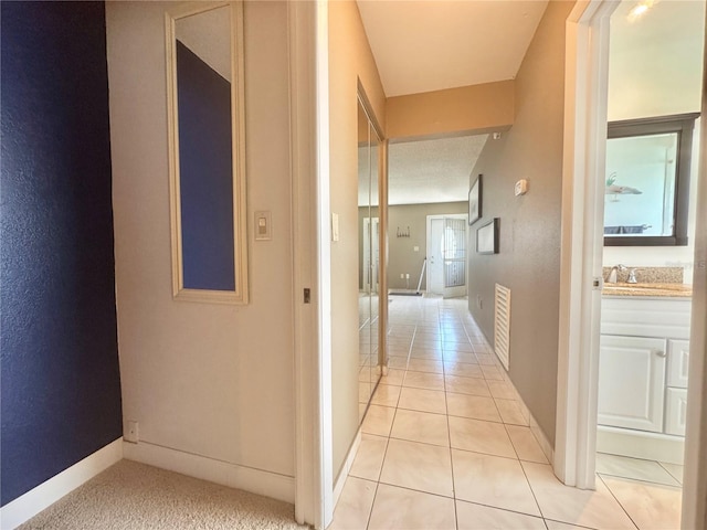 11619 Boynton Ln, New Port Richey, FL 34654 - hallway featuring light tile patterned floors, baseboards, and a sink