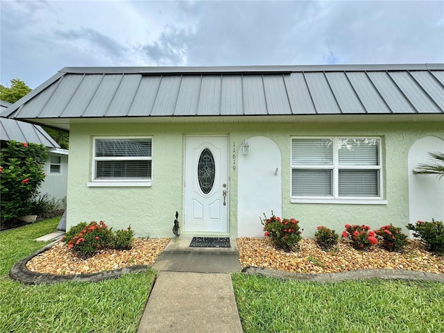 11619 Boynton Ln, New Port Richey, FL 34654 - view of front of house featuring stucco siding, metal roof, and a standing seam roof