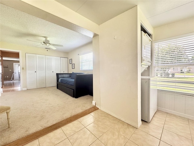 11619 Boynton Ln, New Port Richey, FL 34654 - bedroom featuring light tile patterned floors, light colored carpet, ceiling fan, a textured ceiling, and baseboards