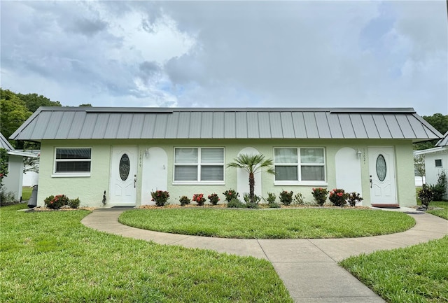 11619 Boynton Ln, New Port Richey, FL 34654 - view of front of property with stucco siding, a metal roof, a front lawn, and a standing seam roof