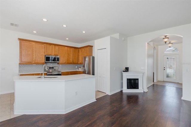 15159 Durango Cir, Brooksville, FL 34604 - kitchen featuring stainless steel appliances, arched walkways, a sink, light countertops, and backsplash