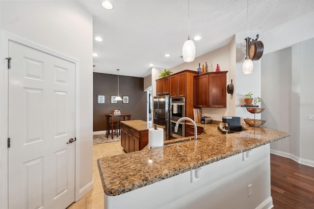 3243 Stonegate Falls Dr, Land O Lakes, FL 34638 - kitchen featuring baseboards, light stone countertops, a kitchen bar, a peninsula, and brown cabinets