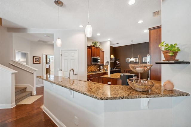 3243 Stonegate Falls Dr, Land O Lakes, FL 34638 - kitchen with brown cabinets, dark wood-style floors, a breakfast bar, tasteful backsplash, and recessed lighting