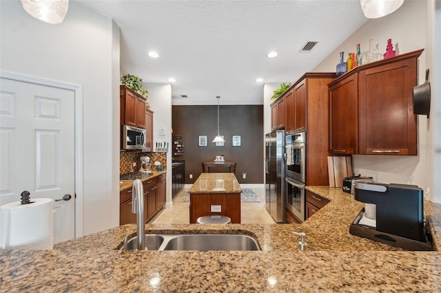 3243 Stonegate Falls Dr, Land O Lakes, FL 34638 - kitchen with appliances with stainless steel finishes, a kitchen island, light stone countertops, recessed lighting, and decorative light fixtures