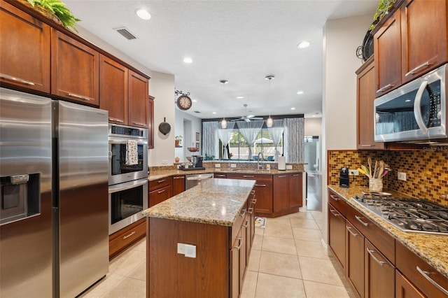 3243 Stonegate Falls Dr, Land O Lakes, FL 34638 - kitchen with appliances with stainless steel finishes, a peninsula, a center island, a sink, and light tile patterned flooring