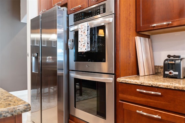 3243 Stonegate Falls Dr, Land O Lakes, FL 34638 - kitchen with stainless steel appliances, brown cabinets, and light stone counters