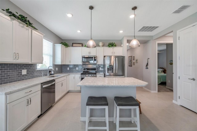 8431 Ocean Tides Cv, Parrish, FL 34219 - kitchen with stainless steel appliances, a sink, tasteful backsplash, a center island, and a breakfast bar area