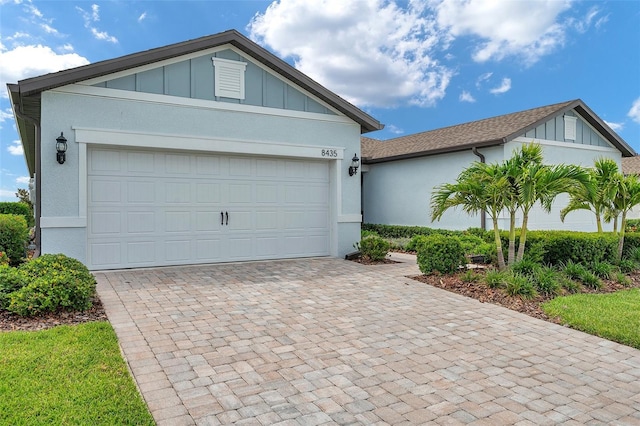 8431 Ocean Tides Cv, Parrish, FL 34219 - view of front of home featuring decorative driveway, a garage, board and batten siding, and stucco siding