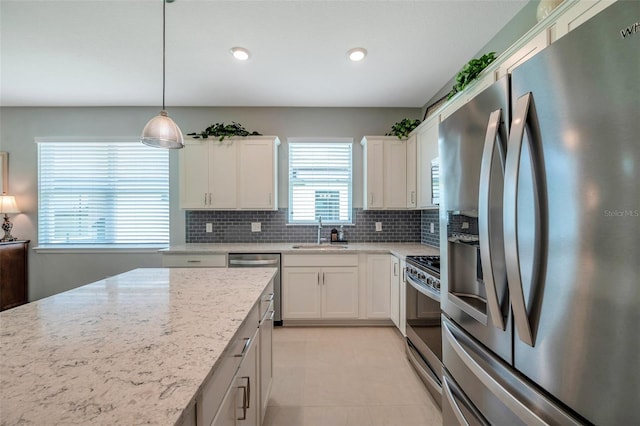 8431 Ocean Tides Cv, Parrish, FL 34219 - kitchen featuring appliances with stainless steel finishes, a sink, backsplash, white cabinetry, and light stone countertops