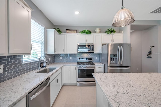 8431 Ocean Tides Cv, Parrish, FL 34219 - kitchen featuring appliances with stainless steel finishes, a sink, white cabinetry, light stone countertops, and decorative backsplash
