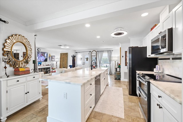 5340 Pilots Pl, New Port Richey, FL 34652 - kitchen with appliances with stainless steel finishes, stone tile floors, white cabinets, a center island with sink, and open floor plan
