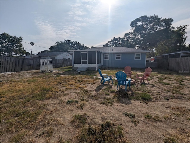 2004 Culberson Ave, Dunedin, FL 34698 - back of house with a sunroom, a fenced backyard, and a fire pit