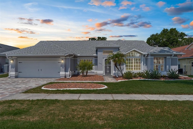 single story home with a garage, stucco siding, and a front lawn