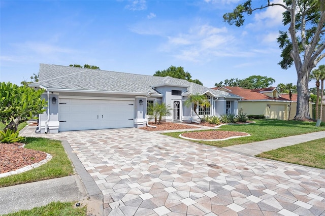 ranch-style home with decorative driveway, stucco siding, a front lawn, and an attached garage