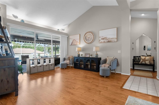 living area featuring high vaulted ceiling, wood finished floors, and baseboards