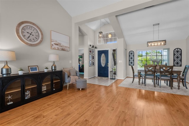 entrance foyer with light wood-style flooring, baseboards, high vaulted ceiling, and a chandelier