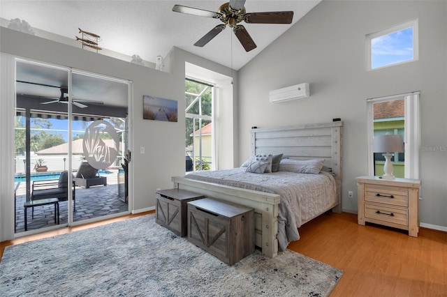 bedroom with an AC wall unit, access to outside, light wood finished floors, lofted ceiling, and baseboards