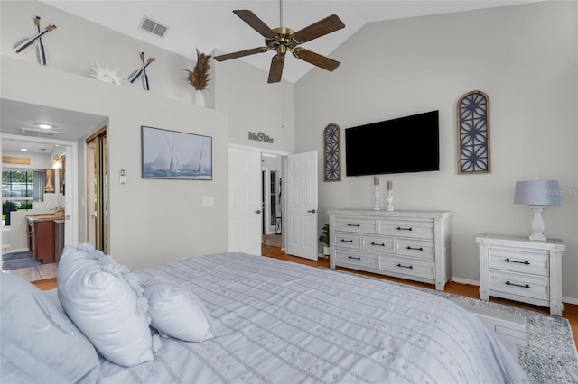 bedroom with high vaulted ceiling, ensuite bath, and a ceiling fan