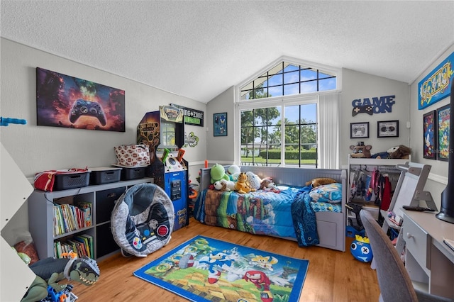 playroom featuring vaulted ceiling, a textured ceiling, and wood finished floors
