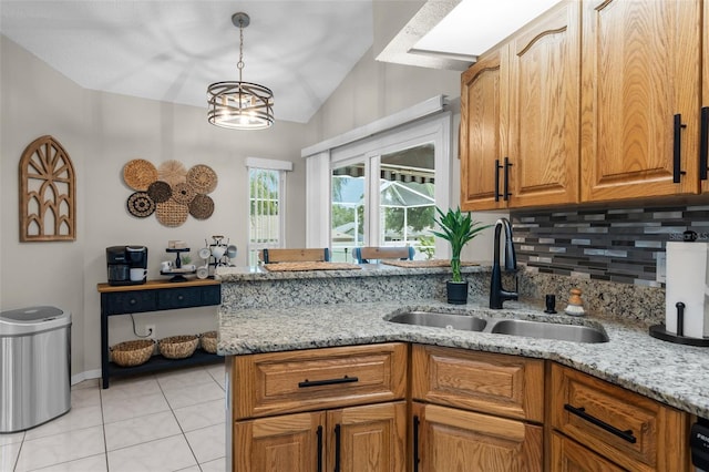 kitchen featuring a sink, tasteful backsplash, lofted ceiling, light tile patterned floors, and light stone counters