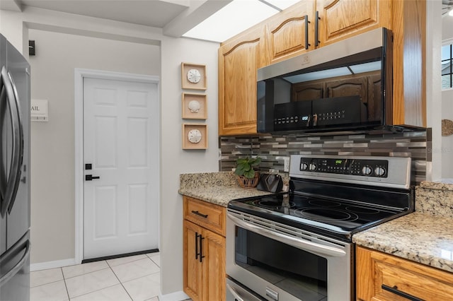 kitchen with stainless steel appliances, decorative backsplash, baseboards, light stone countertops, and light tile patterned floors