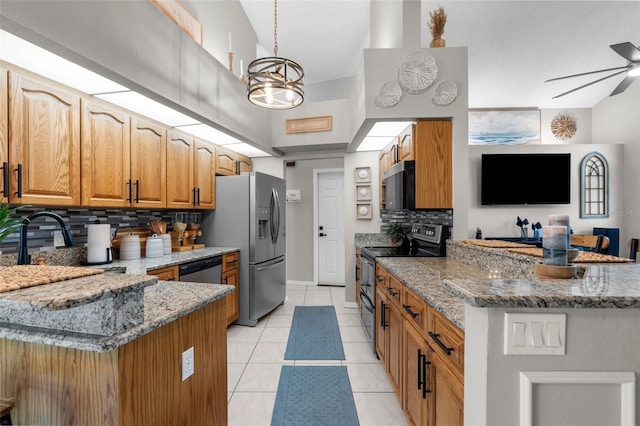 kitchen featuring appliances with stainless steel finishes, a peninsula, tasteful backsplash, light stone counters, and a towering ceiling