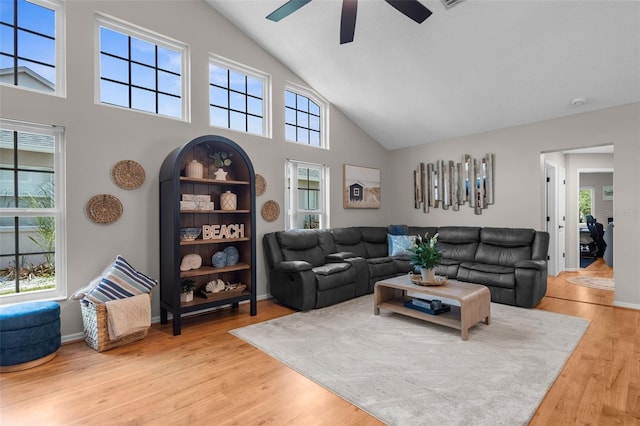 living room with high vaulted ceiling, ceiling fan, and light wood-type flooring