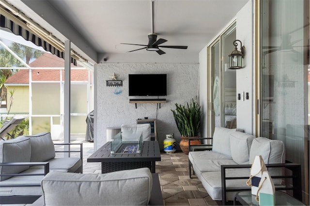view of patio / terrace with an outdoor living space with a fire pit, a ceiling fan, and glass enclosure