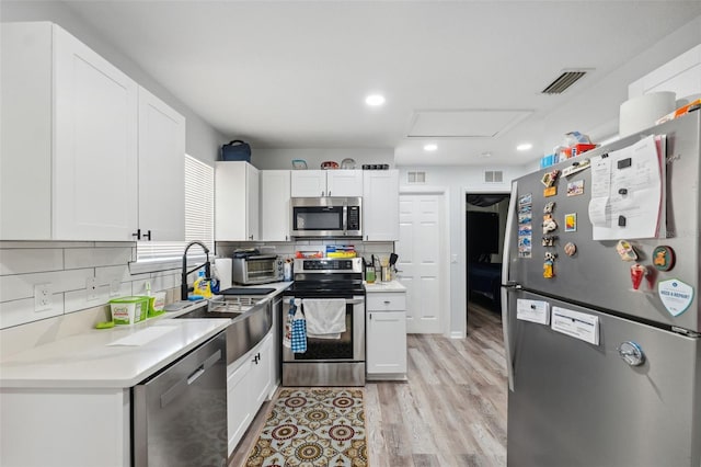 4737 6th St, Zephyrhills, FL 33542 - kitchen with stainless steel appliances, a sink, light wood finished floors, tasteful backsplash, and white cabinetry