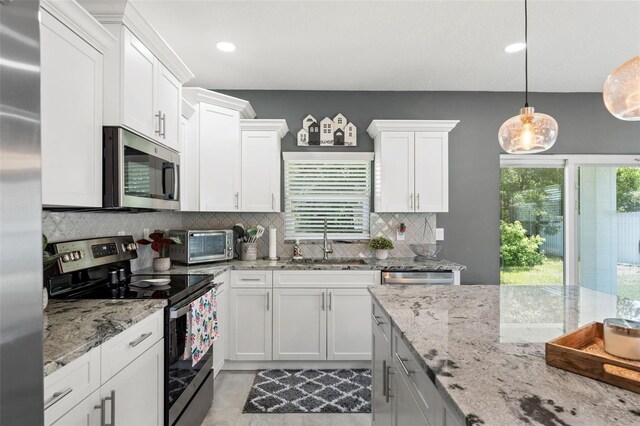 5328 Baldock Ave, Spring Hill, FL 34608 - kitchen featuring stainless steel appliances, tasteful backsplash, white cabinetry, pendant lighting, and light stone countertops