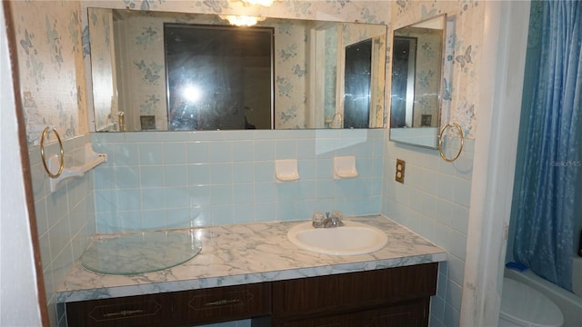 5636 Dolores Dr, Holiday, FL 34690 - full bathroom featuring toilet, double vanity, decorative backsplash, wallpapered walls, and shower / tub combo
