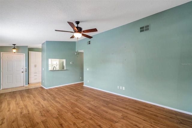 9212 Estrada Pl, New Port Richey, FL 34655 - empty room with a ceiling fan, baseboards, wood finished floors, vaulted ceiling, and a textured ceiling