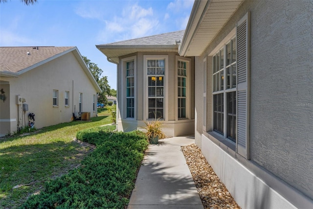 9407 Burnam Dr, Weeki Wachee, FL 34613 - property entrance with stucco siding, a shingled roof, and a lawn
