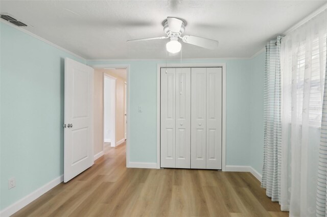 4942 Blue Heron Dr, New Port Richey, FL 34652 - unfurnished bedroom featuring light wood finished floors, baseboards, a closet, ornamental molding, and a ceiling fan