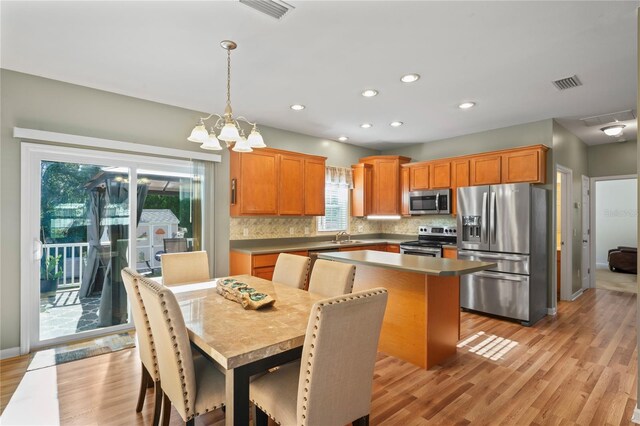 15613 Charmwood Dr, Hudson, FL 34667 - kitchen with appliances with stainless steel finishes, a sink, a chandelier, tasteful backsplash, and light wood-style flooring